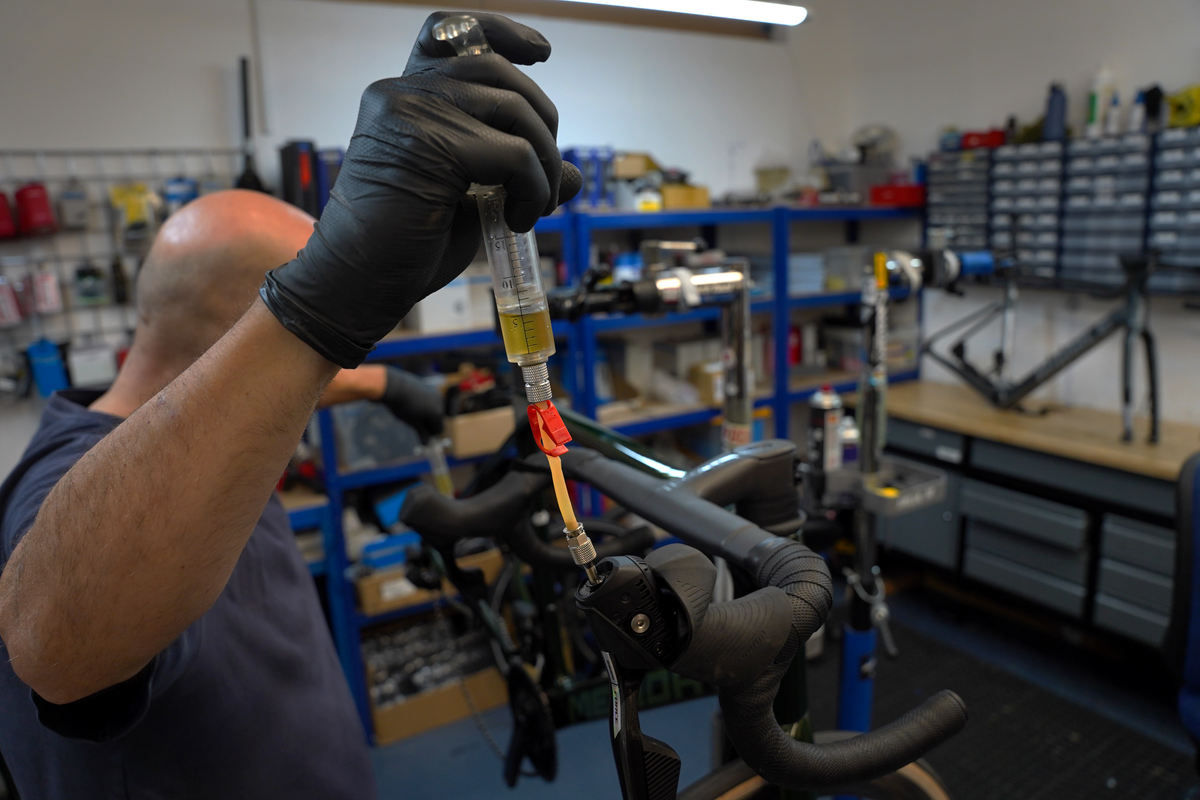 A mechanic bleeding brakes in the Cycle Exchange workshop
